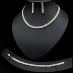 Baguette CZ tennis jewelry set wholesale including necklace, drop earrings, and tennis bracelet featuring emerald-cut cubic zirconia on 18K gold and palladium plated copper.