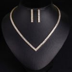 Square CZ V-necklace set wholesale including V-shaped tennis necklace and matching linear dangle drop earrings featuring princess-cut cubic zirconia on 18K gold and palladium plated copper base.