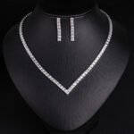 Square CZ V-necklace set wholesale including V-shaped tennis necklace and matching linear dangle drop earrings featuring princess-cut cubic zirconia on 18K gold and palladium plated copper base.