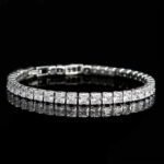 Square CZ V-necklace set wholesale including V-shaped tennis necklace and matching linear dangle drop earrings featuring princess-cut cubic zirconia on 18K gold and palladium plated copper base.
