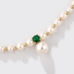 Niche small pearl necklace jewelry set wholesale featuring delicate round faux pearls, an emerald-green cubic zirconia center accent, and matching pearl stud earrings from junejewelry.com