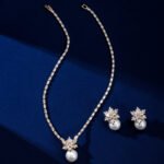Niche snowflake pearl pendant jewelry set wholesale featuring a cubic zirconia tennis necklace with a snowflake crystal star burst and smooth pearl pendant, paired with matching pearl drop earrings from junejewelry.com