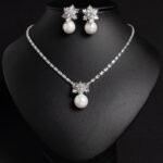 Niche snowflake pearl pendant jewelry set wholesale featuring a cubic zirconia tennis necklace with a snowflake crystal star burst and smooth pearl pendant, paired with matching pearl drop earrings from junejewelry.com