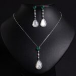 Niche teardrop shell pearl zircon jewelry set wholesale featuring a pear-shaped mother-of-pearl drop topped with a round green agate gem and crystal linear chain, paired with matching drop earrings from junejewelry.com