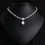 Light luxury tear drop pearl strand necklace wholesale featuring a delicate white pearl bead chain with a pave CZ arched crown connector and large teardrop pearl pendant from junejewelry.com