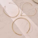 Model wearing gold plated minimalist rigid wire torque collar choker necklace in stainless steel