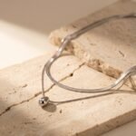 Model wearing double layer gold teardrop pendant necklace with flat snake chain