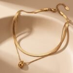 Model wearing double layer gold teardrop pendant necklace with flat snake chain