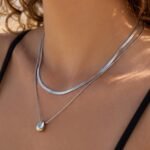 Model wearing double layer gold teardrop pendant necklace with flat snake chain