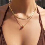 Model wearing double layer gold teardrop pendant necklace with flat snake chain