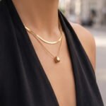 Model wearing double layer gold teardrop pendant necklace with flat snake chain