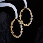 Cubic zirconia oval hoop earrings featuring continuous prong-set round stones, available in gold and silver tones in two sizes.