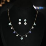 Niche floral charm pearl necklace earring set wholesale featuring alternating enamel flower charms and high-luster round pearl drops along a gold link chain with matching flower pearl drop earrings from junejewelry.com