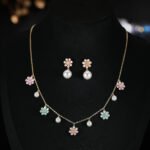 Niche floral charm pearl necklace earring set wholesale featuring alternating enamel flower charms and high-luster round pearl drops along a gold link chain with matching flower pearl drop earrings from junejewelry.com