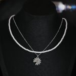 Niche layered daisy pearl necklace wholesale featuring a dual-strand design with a full pearl choker strand and a fine silver chain suspending a micro-pave cubic zirconia daisy pendant from junejewelry.com