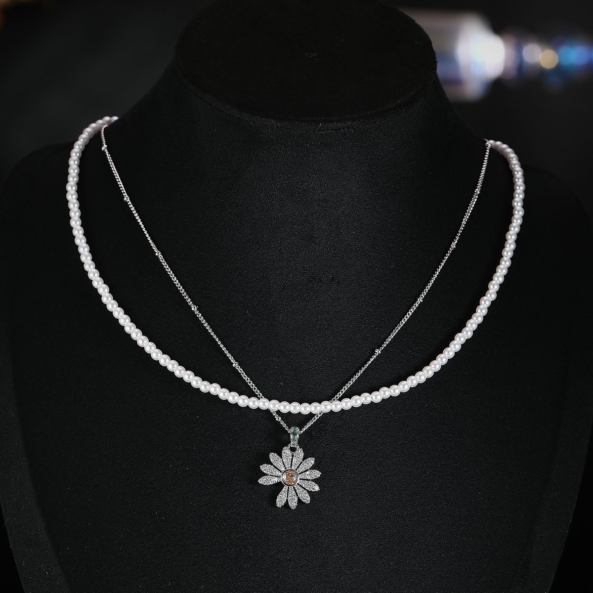 Niche layered daisy pearl necklace wholesale featuring a dual-strand design with a full pearl choker strand and a fine silver chain suspending a micro-pave cubic zirconia daisy pendant from junejewelry.com