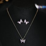 Niche ice translucent butterfly zircon jewelry set wholesale featuring carved crystal butterfly wings with marquise zircon bodies on a fine chain pendant necklace and matching stud earrings from junejewelry.com