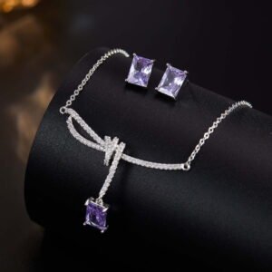 Niche purple zircon bow ribbon necklace earring set wholesale featuring a paved ribbon bow pendant suspending a rectangular emerald-cut purple zircon stone, paired with matching purple stud earrings from junejewelry.com