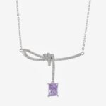 Niche purple zircon bow ribbon necklace earring set wholesale featuring a paved ribbon bow pendant suspending a rectangular emerald-cut purple zircon stone, paired with matching purple stud earrings from junejewelry.com
