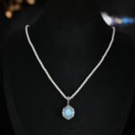 Niche vintage blue gemstone pearl jewelry set wholesale featuring an oval turquoise-blue cabochon surrounded by a halo of micro-pave zircons and turquoise accents on a pearl strand necklace with matching stud earrings from junejewelry.com