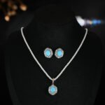 Niche vintage blue gemstone pearl jewelry set wholesale featuring an oval turquoise-blue cabochon surrounded by a halo of micro-pave zircons and turquoise accents on a pearl strand necklace with matching stud earrings from junejewelry.com