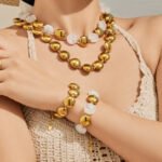 Chunky stainless steel necklace and bracelet jewelry set featuring smooth high-polish round flat disc beads in gold and silver finishes.