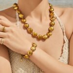 Chunky stainless steel necklace and bracelet jewelry set featuring smooth high-polish round flat disc beads in gold and silver finishes.