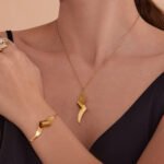 Stainless steel abstract twisted ribbon geometric pendant necklace, chain bracelet, and drop earrings set.