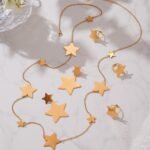 Stainless steel gold star jewelry set featuring long station sweater necklace, drop earrings, and star statement ring.