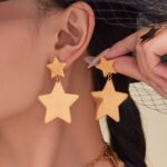 Stainless steel gold star jewelry set featuring long station sweater necklace, drop earrings, and star statement ring.
