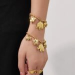 18K gold plated stainless steel elephant charm necklace and bracelet set featuring a prominent central elephant pendant and smaller charm accents on a beaded ball chain.