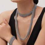 Draped multi-strand liquid chain long necklace and wide cuff bracelet jewelry set in gold, silver, and two-tone stainless steel finishes.