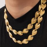Textured ribbed seashell motif link necklace and bracelet set in two-tone gold and silver stainless steel finishes.