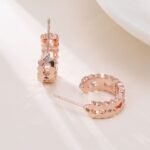 Rose gold cutout hoop earrings featuring scalloped edges, hexagonal cutout pattern, AAA cubic zirconia accents, and 925 sterling silver posts.