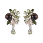 Ornate botanical dangle earrings featuring dual crystal flower blooms, glossy green enamel leaves, a smooth round bead, and a dangling teardrop CZ in silver and gold metal finishes.