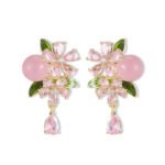 Ornate botanical dangle earrings featuring dual crystal flower blooms, glossy green enamel leaves, a smooth round bead, and a dangling teardrop CZ in silver and gold metal finishes.