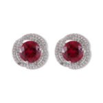 Round ruby stud earrings wholesale featuring a vibrant red central CZ stone wrapped in a swirling pavé cubic zirconia halo with S925 sterling silver posts from junejewelry.com