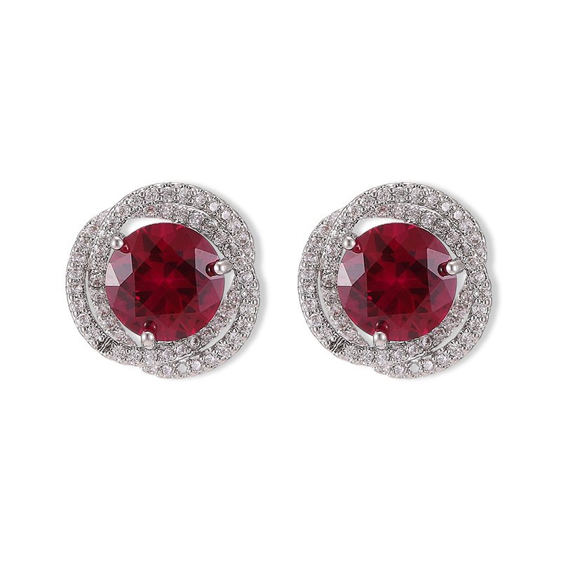 X-048 (1) Round ruby stud earrings wholesale featuring a vibrant red central CZ stone wrapped in a swirling pavé cubic zirconia halo with S925 sterling silver posts from junejewelry.com
