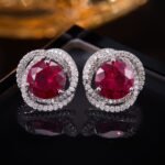 Round ruby stud earrings wholesale featuring a vibrant red central CZ stone wrapped in a swirling pavé cubic zirconia halo with S925 sterling silver posts from junejewelry.com