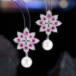 Snowflake CZ freshwater pearl drop earrings featuring an intricate starburst starburst pattern, princess-cut gems, micro-paved borders, and a round freshwater pearl dangle