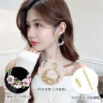 Twisted round hoop earrings adorned with hand-painted enamel flowers, green leaves, and CZ crystal accents in purple and white options.