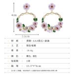 Twisted round hoop earrings adorned with hand-painted enamel flowers, green leaves, and CZ crystal accents in purple and white options.