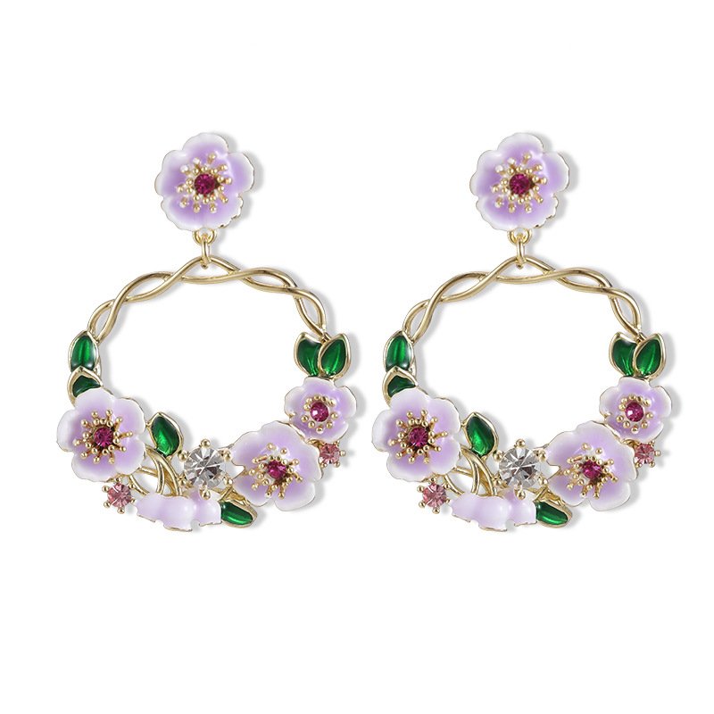 Twisted round hoop earrings adorned with hand-painted enamel flowers, green leaves, and CZ crystal accents in purple and white options.