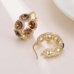 Oval halo CZ hoop earrings featuring faceted oval crystal main stones surrounded by micro-pavé halos on a thick hoop frame with 925 sterling silver posts.