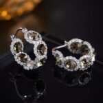 Oval halo CZ hoop earrings featuring faceted oval crystal main stones surrounded by micro-pavé halos on a thick hoop frame with 925 sterling silver posts.