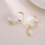 Mother of pearl flower hoop earrings with natural carved shell petals, AAA cubic zirconia accents, and gold-plated huggie hoop closure.