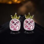 Sparkling pineapple stud earrings featuring marquise-cut crystal crown leaves, lattice fruit body, and micro-pavé accents in yellow, pink, and clear options.