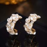 Mother of pearl flower hoop earrings featuring carved shell flower petals, sparkling AAA cubic zirconia accents, 18K gold-plated C-shape hoop base, and 925 sterling silver ear posts.