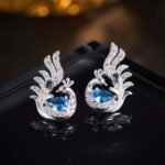 Sculpted peacock-shaped stud earrings set with vibrant pear-cut cubic zirconia stones and pavé feather details, available in emerald green, rose pink, and sapphire blue options.