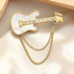 Cool rock style natural mother of pearl guitar brooch pin wholesale featuring 18K real gold plated copper, baguette CZ neck, and draped chain tassels from junejewelry.com